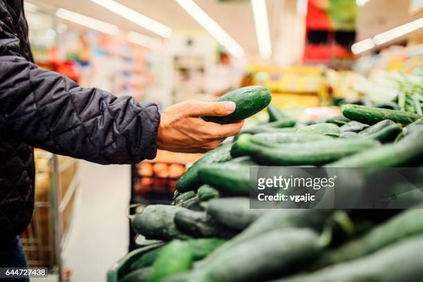 junger mann lebensmittel einkaufen - cucumber stock-fotos und bilder