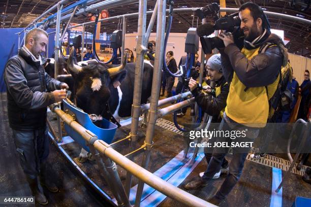Journalists film a man giving food to the mascot cow Fine upon its arrival at the Salon de l'Agriculture on February 24 in Paris. Nearly 4,000...