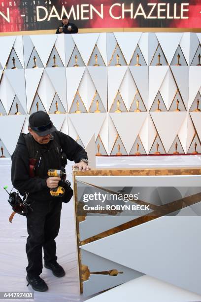 Worker builds the red carpet arrivals area ahead of the 89th annual Oscars outside the Dolby Theater in Hollywood, California on February 23, 2017....