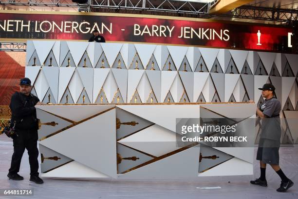 Workers build the red carpet arrivals area ahead of the 89th annual Oscars outside the Dolby Theater in Hollywood, California on February 23, 2017....