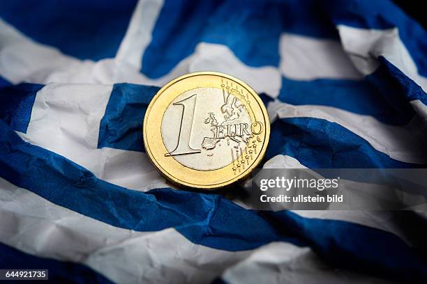 Euromünze auf zerknitterter Griechenlandfahne, Symbolfoto Schuldenstreit