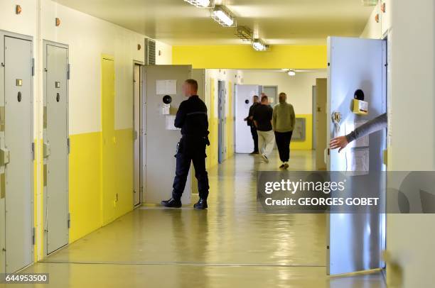 Inmates and guard walk down a hallway of cells at Mont-de-Marsan prison, in Mont-de-Marsan, on January 26, 2017. The prison was chosen as the site to...