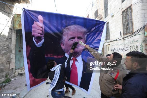 Palestinians hit a US President Donald Trump poster to condemn Trump's policies as they stage a protest against Israeli Government's violations over...