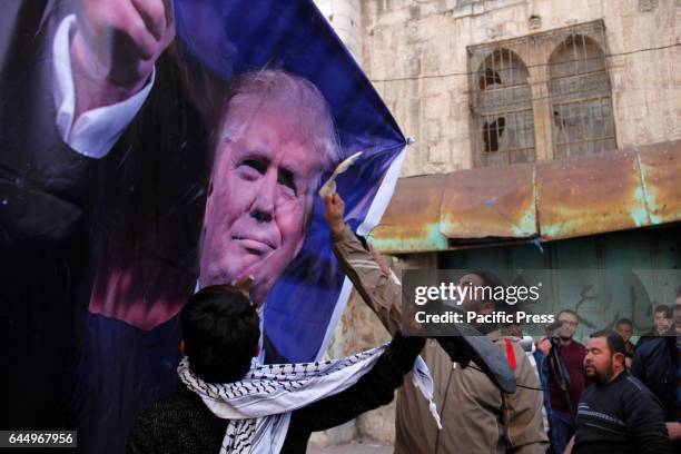 Palestinians throw shoes at a banner with a picture of US President Donald J. Trump during a protest near checkpoint 56 at the entrance of Shuhada...