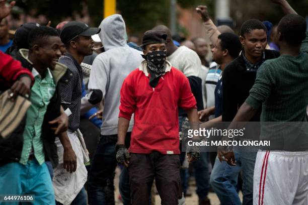 Masked South African demonstrator looks on during stand off with a group of migrants in the center of Pretoria on February 24, 2017. - South African...