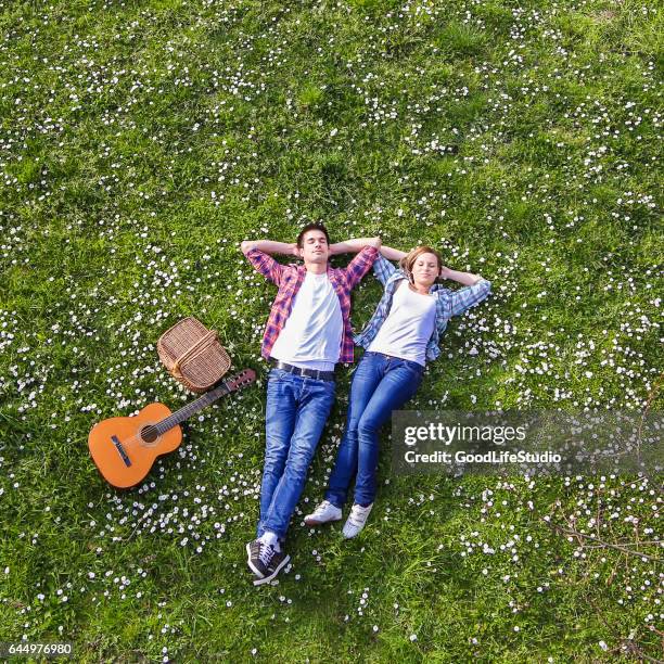 young couple enjoying springtime - laying on grass stock pictures, royalty-free photos & images