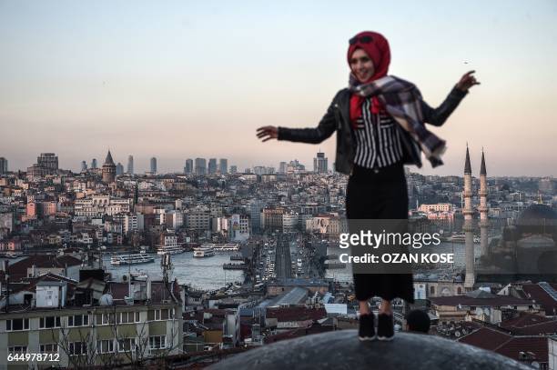 Woman poses on the roof of the Buyuk Valide Han in the district of Eminonu as the Bosphorus is seen in the background on February 24, 2017 in...