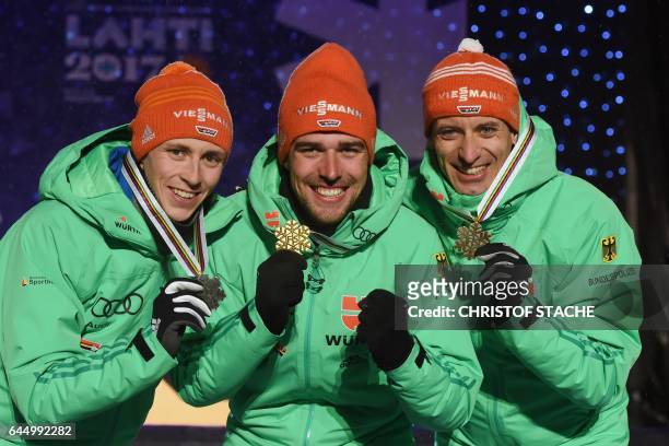 Second placed Eric Frenzel, winner Johannes Rydzek and third placed Bjoern Kircheisen of Germany celebrate during the medals ceremony for men's...