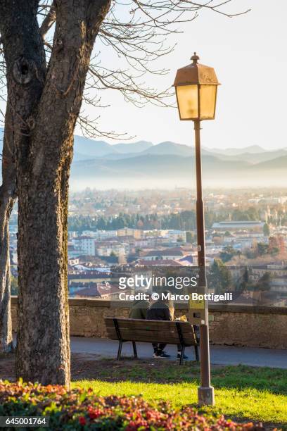 people on a bench in città alta (upper town). bergamo, italy. - bergamo stock photos et images de collection