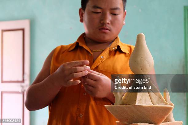 Novizen des buddhistischen Tempels von Singhik bei der Herstellung von Torma, verschieden geformten Opferkuchen aus Teig und gefärbter Butter,...