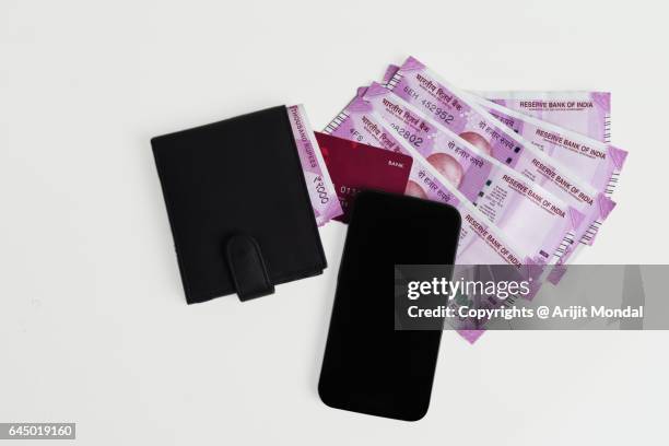 top view of office desk with new indian currency notes of 2000 rupee, mobile phone, wallet and credit cards - gandhi stock-fotos und bilder