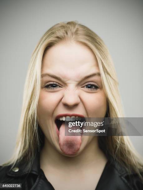 excited woman sticking out tongue against gray background - sticking out tongue stock pictures, royalty-free photos & images