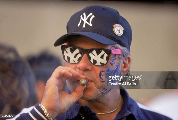View of a New York Yankee fan wearing a Yankee Logo as he smokes a cigar taken before Game 1 of the World Series against the New York Mets at Yankee...
