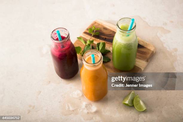 3 fresh bottles of fruit juice with drinking straw. - beetroot juice stock-fotos und bilder