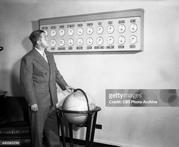 Radio news editor and producer, Paul White, is photographed in front of an array of wall clocks, featuring the time from zones and cities from around...