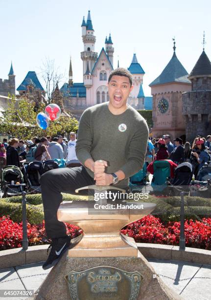 In this handout photo provided by Disney Parks, 'Daily Show' host Trevor Noah tries his luck at removing the Sword in the Stone in Fantasyland at...