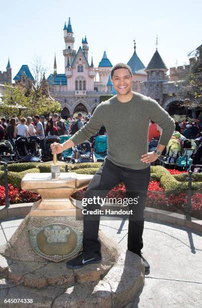 In this handout photo provided by Disney Parks, 'Daily Show' host Trevor Noah tries his luck at removing the Sword in the Stone in Fantasyland at...