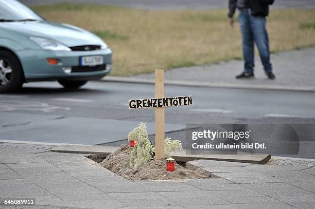 Nachgestelltes Grab mit Grablichtern, Holzkreuz und Inschrift Grenzen töten am Oranienplatz in Berlin-Kreuzberg. Offenbar Nachahmung der Kunstaktion...