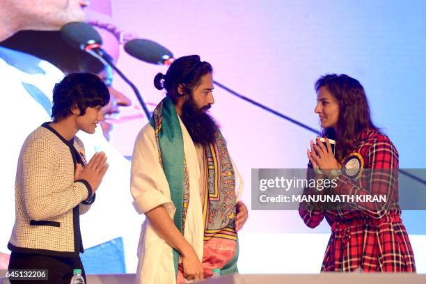 Indian wrestlers Babita and Geeta Phogat appear onstage with Akshar Power Yoga Foundation Master Akshar during a yoga and self-defence lesson for...