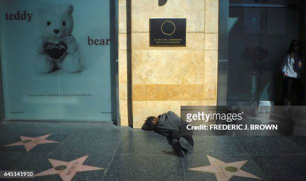 Man, wrapped in a blanket, sleeps on the Walk of Fame sidewalk in front of the Museum of Broken Relations in Hollywood, California on February 22 a...