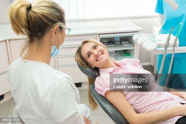 junge patientin lächelnd bei zahnarzt - zahnarztstuhl stock-fotos und bilder