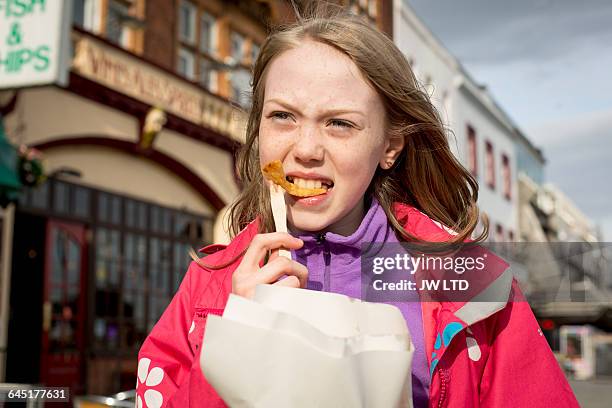 girl (8-9) eating chips, seaside - fish chips stockfoto's en -beelden