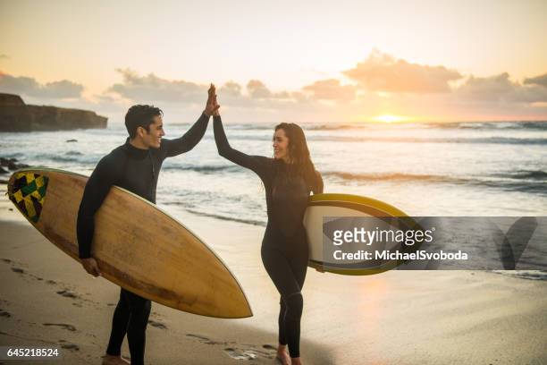 silhouette von ein paar hohe fiving mit ihren surboards - san diego stock-fotos und bilder