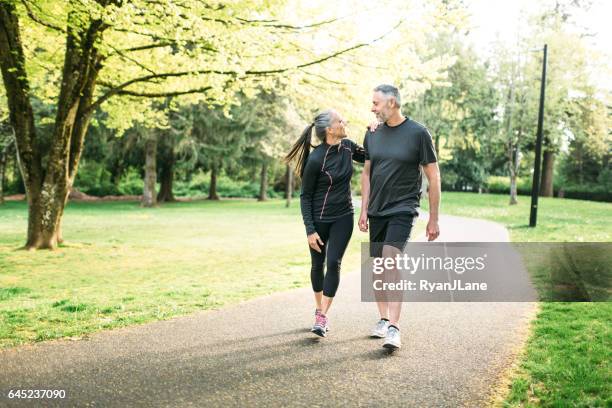 mature couple exercising outdoors - man walking in a park stock pictures, royalty-free photos & images