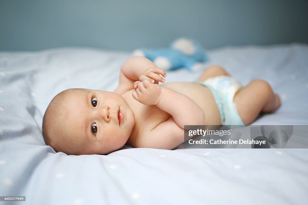 A 4 month old baby boy laying on a bed