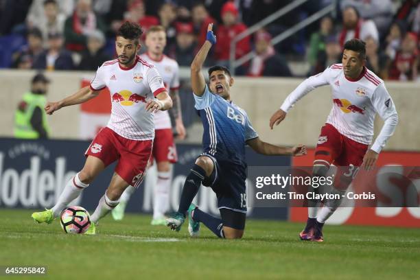 Matias Laba of Vancouver Whitecaps is tackled by Felipe Martins of New York Red Bulls watched by Gonzalo Veron of New York Red Bulls during the New...