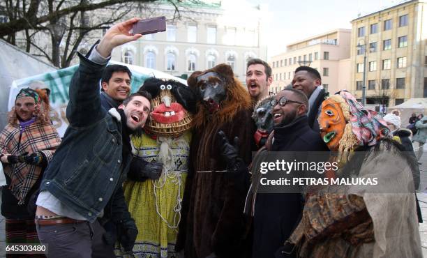 Man takes a selfie with costumed person during revellers parade through the streets of the old town of Vilnius to celebrate Uzgavenes or 'the time...