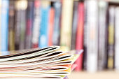 edge of colorful magazine stacking with  blurry bookshelf