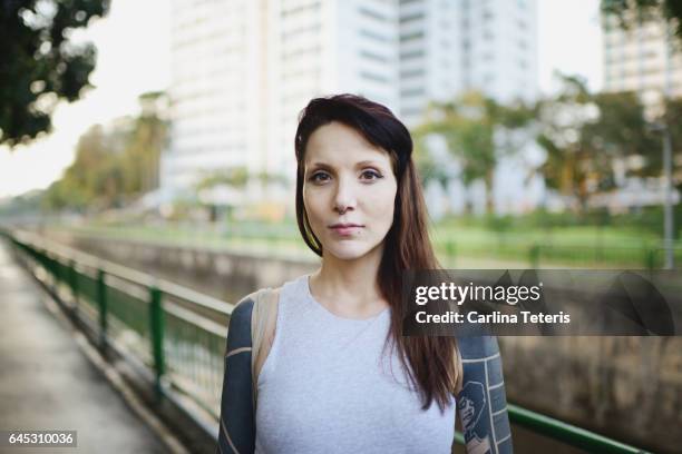 woman with tatoos standing in a park - femme enceinte jardin photos et images de collection