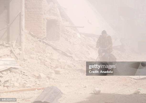 Syrian man rides his bicycle through smoke after Assad Regime's airstrike over civilians in residential areas at the Douma town of Eastern Goutha in...
