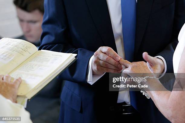 wedding ring being put on brides finger - wedding alter stock pictures, royalty-free photos & images