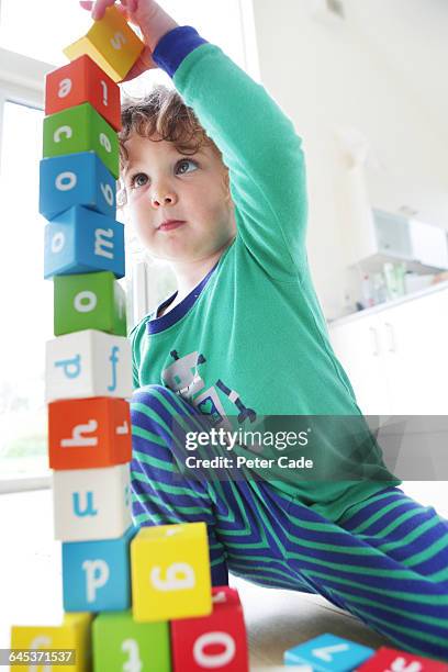 young child stacking alphabet bricks - tower stock-fotos und bilder