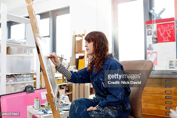 artist at work in her studio - female artist painting stock-fotos und bilder