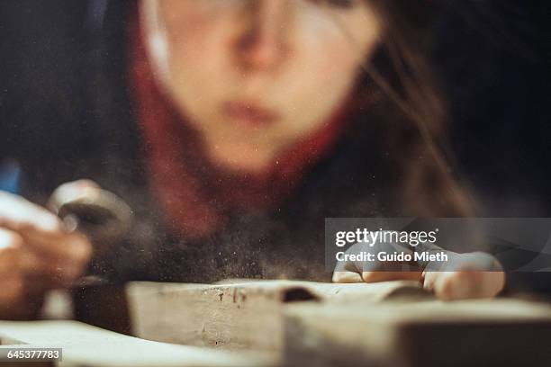 woman blowing away wood shavings. - diy woman stock-fotos und bilder