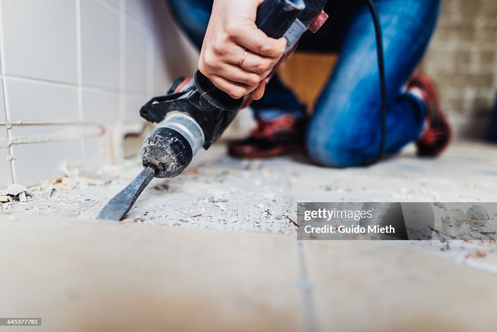 Woman removing old tiles.