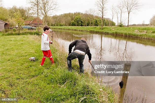 father fishing soccer ball from ditch for son - ditch stock pictures, royalty-free photos & images