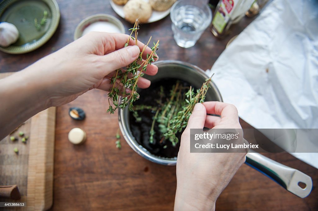 Adding thyme to a cooking pot