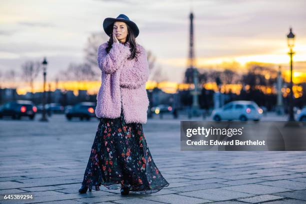 Kristina Castillo, fashion and life style blogger, wears a SHE pink fur coat, Celine black boots, a Mango black dress with floral print, a Mango hat,...