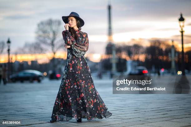 Kristina Castillo, fashion and life style blogger, wears Celine black boots, a Mango black dress with floral print, a Mango hat, and a Furla bag, at...