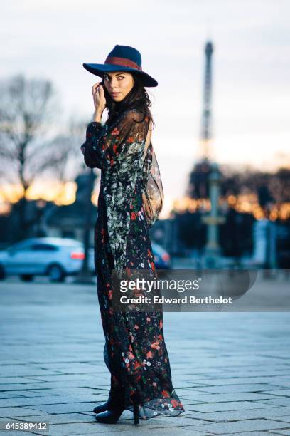 Kristina Castillo, fashion and life style blogger, wears Celine black boots, a Mango black dress with floral print, a Mango hat, and a Furla bag, at...