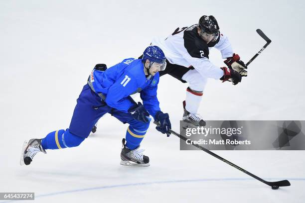 Mei Ushu of Japan and Ilya Kovzalov of Kazakhstan battle for the puck in the men's ice hockey match between Japan and Kazakhstan on day nine of the...