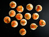 Smoked Salmon and soft chees canapes appetizers with chives on black table