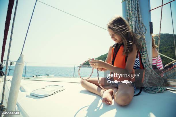 mädchen binden von knoten im urlaub auf segelboot - kid sailing stock-fotos und bilder