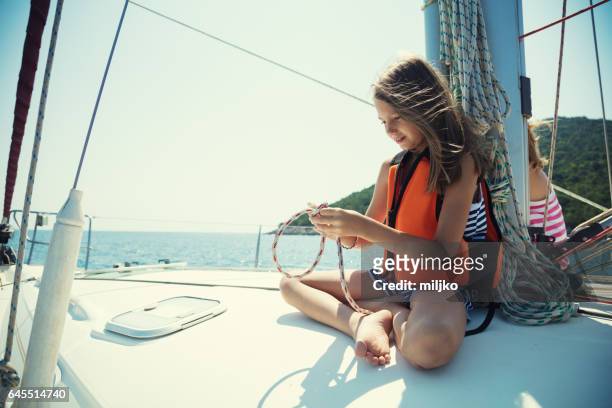 girl tying knots on vacation on sailboat - kid sailing imagens e fotografias de stock