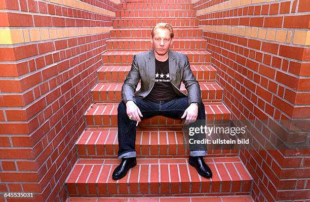Auf den Stufen seiner roten Ziegelsteintreppe an seiner GARTEN - WOHNUNG , in BERIN MITTE