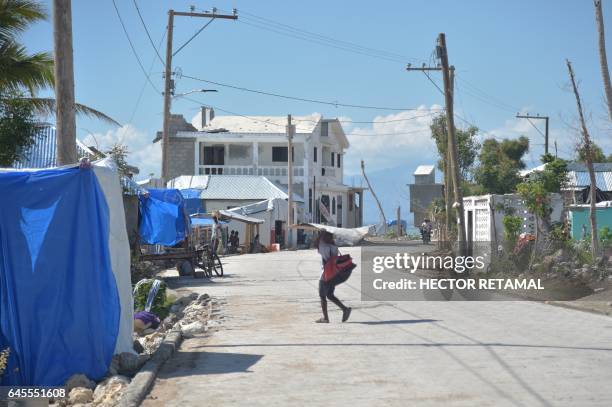 Child walks carrying metal for the roof of his house in the commune of Coteaux, southwestern Haiti, on February 25 that was affected by the passage...